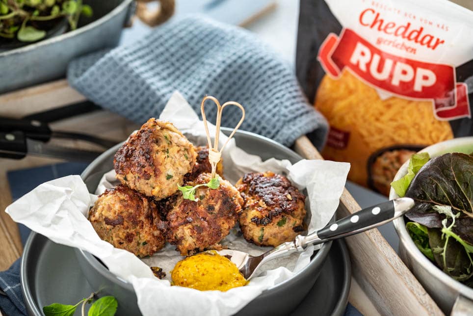 auf einem Tablett steht ein Teller mit Fleischbällchen und Besteck