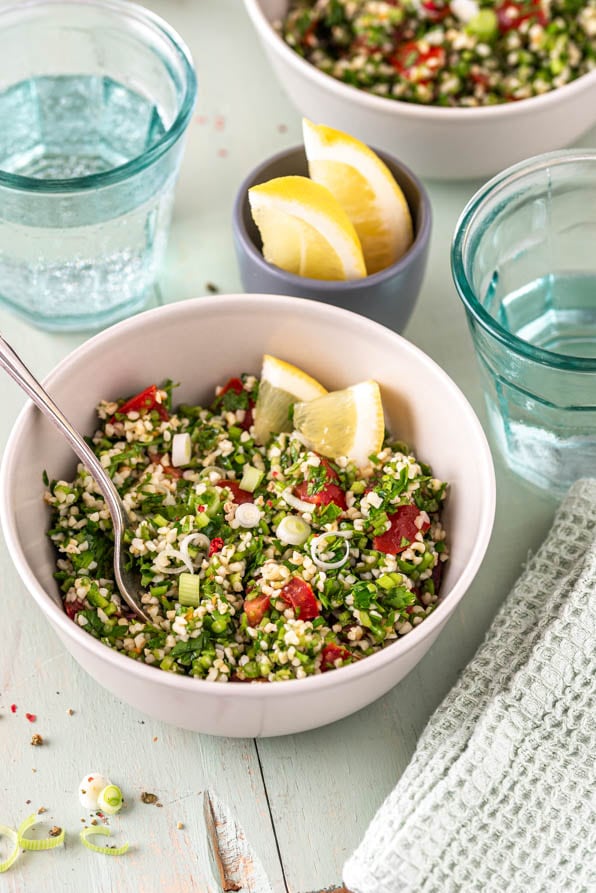 Zwei Schüsseln mit Tabouleh und Gläsern auf Tisch