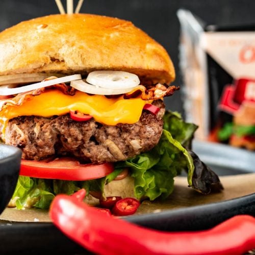 Ein Burger mit Rindfleisch, Zwiebeln und Salat wurde mit Sauce auf einem Teller angerichtet