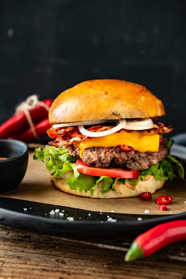 Ein Burger mit Rindfleisch, Zwiebeln und Salat wurde mit Sauce auf einem Teller angerichtet