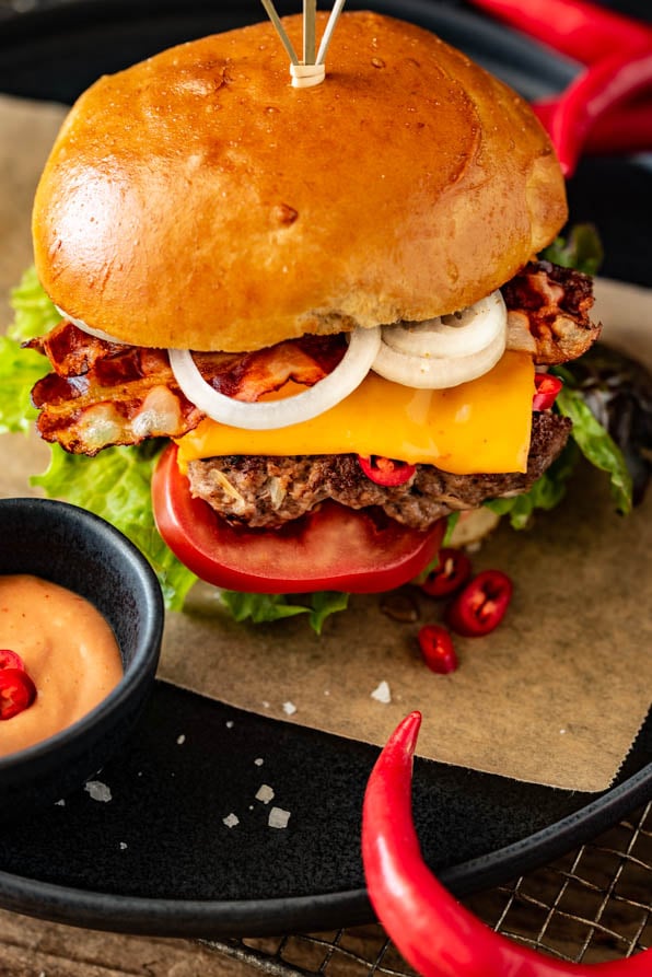 Ein Burger mit Rindfleisch, Zwiebeln und Salat wurde mit Sauce auf einem Teller angerichtet