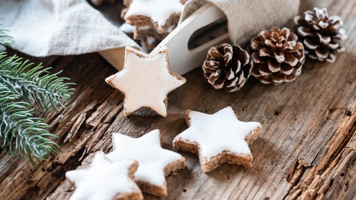 zimtsterne-einfach-und-schnell Einige Zimtsterne liegen mit Weihnachtsdekoration am Tisch