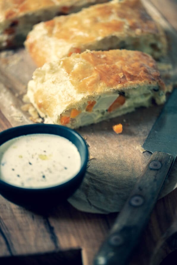 aufgeschnittener Gemüsetrudel auf Brett mit Sauce