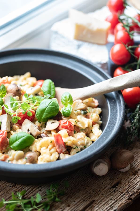 Spätzle mit Tomaten und Basilikum in einer grauen Pfanne