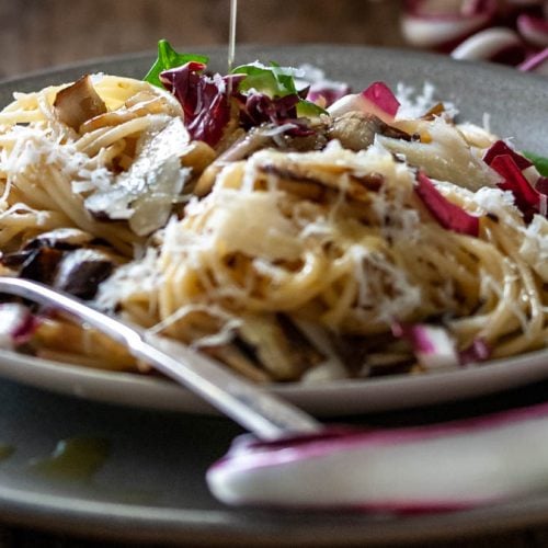 Ein Teller mit Spaghetti und gebratenem Radicchio steht am Tisch