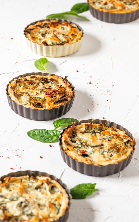 Mehrere kleine Förmchen mit Spinat Quiche
