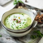 Cremige Kräutersuppe mit Croutons steht auf Tablett