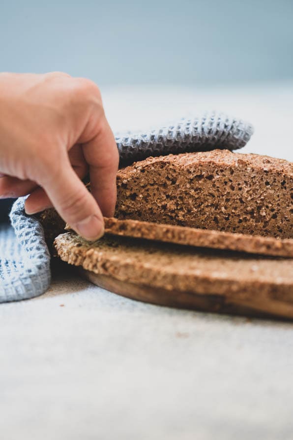 Eine Hand greift zu einer Scheibe Brot