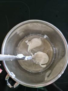 Joghurt wird zu flüssiger Gelatine in Topf gegeben