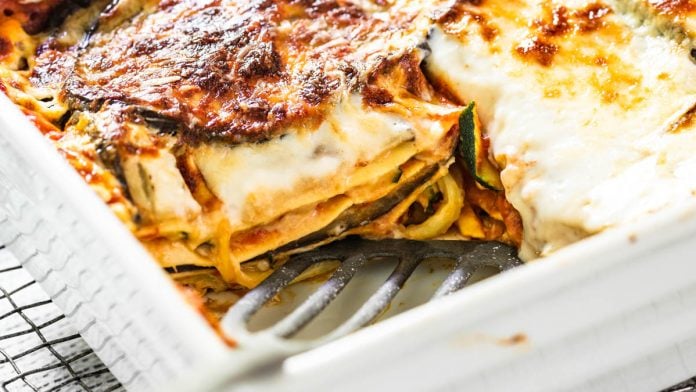 Auflaufform mit Gemüselasagne mit Zucchini und Aubergine steht auf einem Gitter