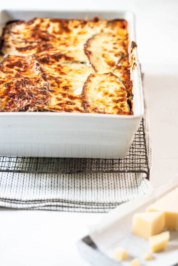 Auflaufform mit Gemüselasagne mit Zucchini und Aubergine steht auf einem Gitter
