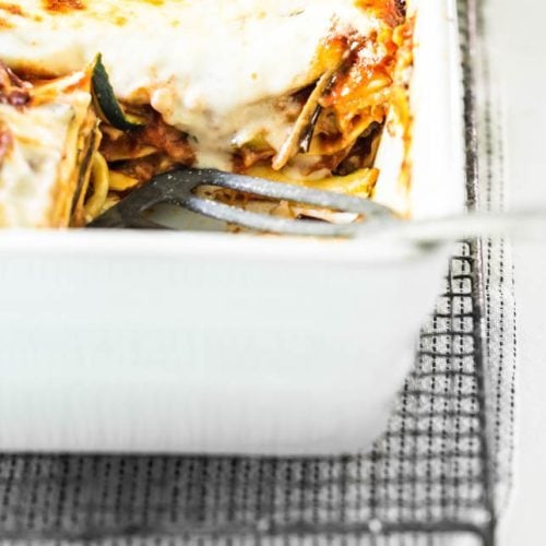 Auflaufform mit Gemüselasagne mit Zucchini und Aubergine steht auf einem Gitter