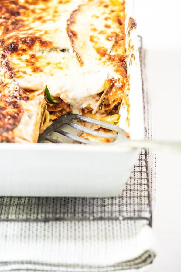 Auflaufform mit Gemüselasagne mit Zucchini und Aubergine steht auf einem Gitter