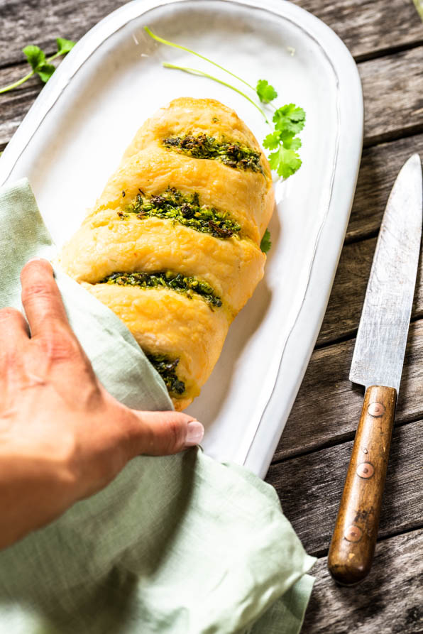 eine Hand greift nach Baguette mit Knoblauchbutter