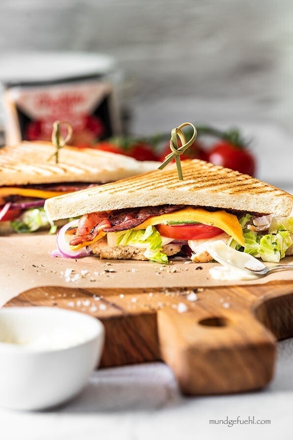 Club Sandwich mit Hähnchen ist auf einem Holzbrett angerichtet