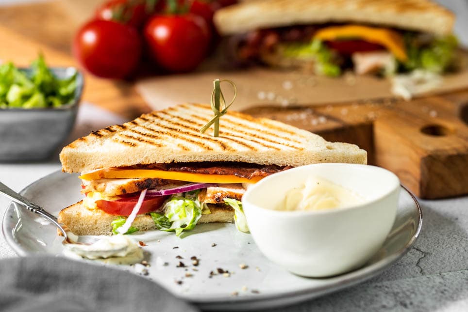 Club Sandwich ist mit Aioli auf einem Teller angerichtet
