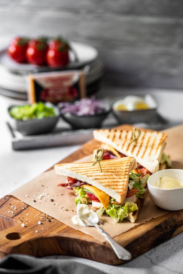 Club Sandwich ist mit Aioli auf einem Teller angerichtet