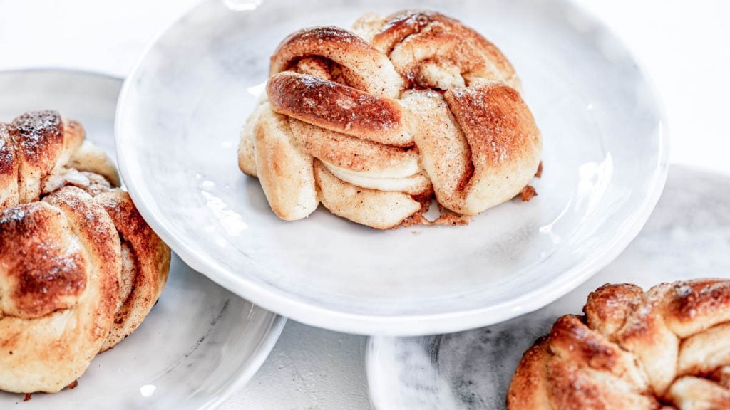 Schwedische Zimtschnecken stehen auf 3 Tellern