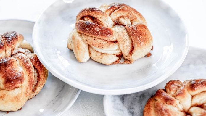 Schwedische Zimtschnecken stehen auf 3 Tellern