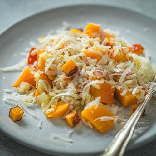 Risotto mit Kürbis und Speck auf einem Teller