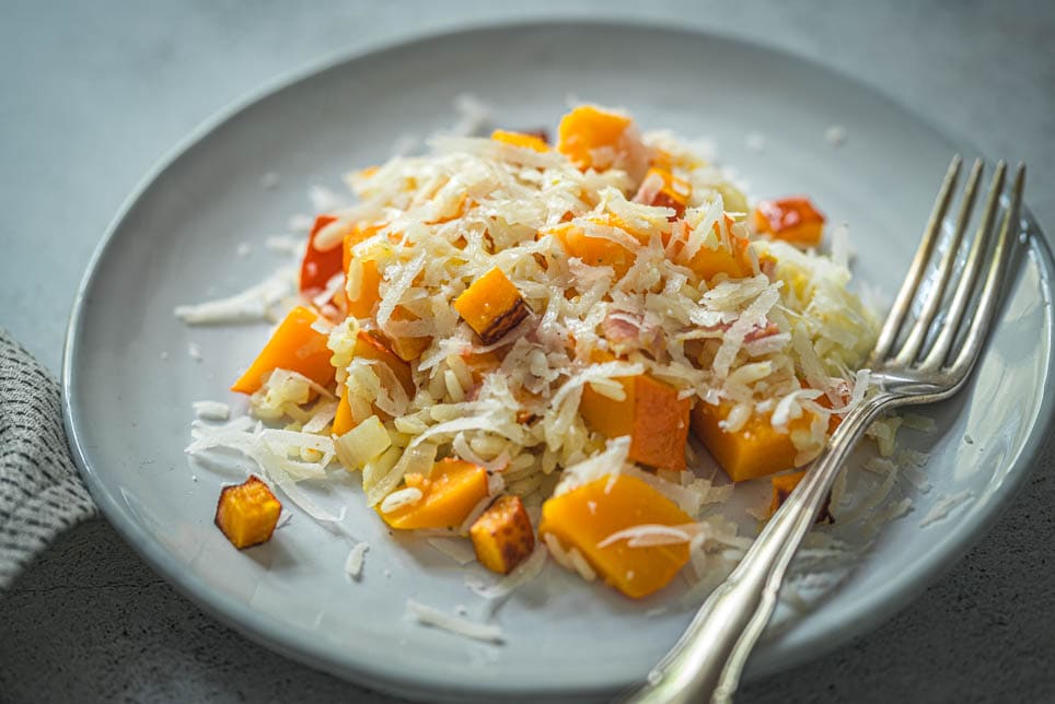 Risotto mit Kürbis und Speck auf einem Teller