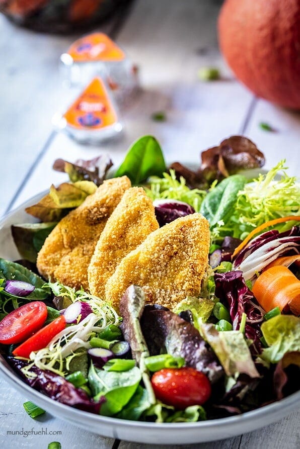 Bunter Salat wurde mit Kartoffel-Kürbis-Ecken auf einem Teller angerichtet