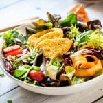 Bunter Salat wurde mit Kartoffel-Kürbis-Ecken auf einem Teller angerichtet