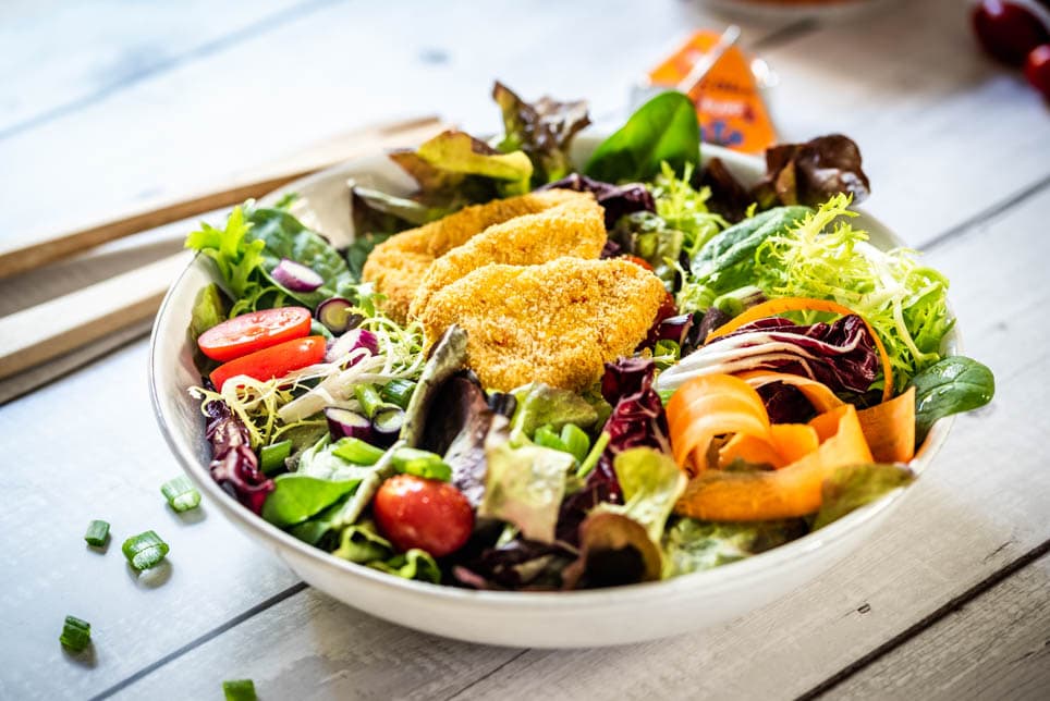 Bunter Salat wurde mit Kartoffel-Kürbis-Ecken auf einem Teller angerichtet