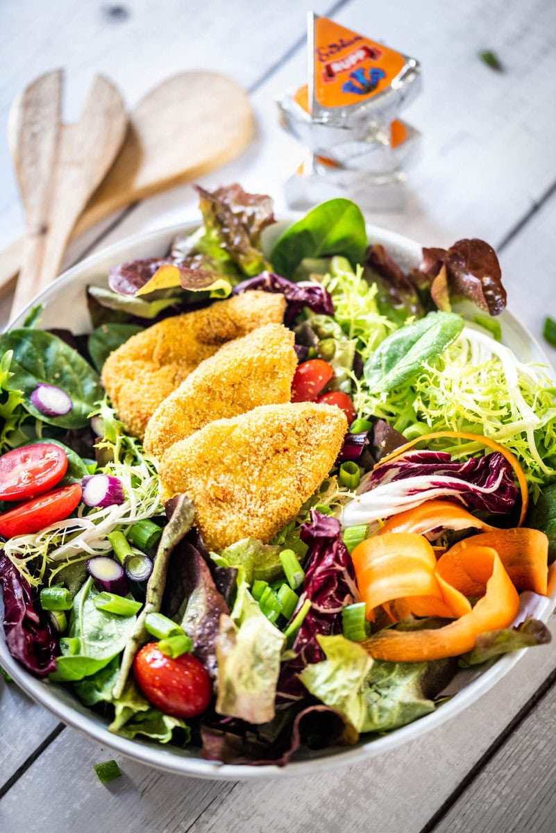 Bunter Salat wurde mit Kartoffel-Kürbis-Ecken auf einem Teller angerichtet