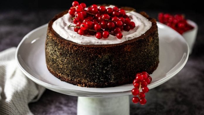 Mohntorte garniert mit Ribiseln steht auf Tortenständer