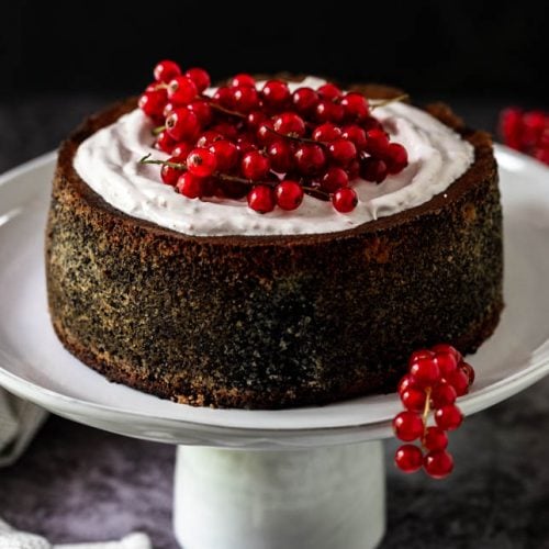 Mohntorte garniert mit Ribiseln steht auf Tortenständer