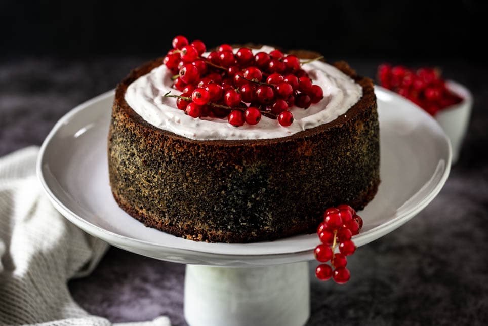 Mohntorte garniert mit Ribiseln steht auf Tortenständer