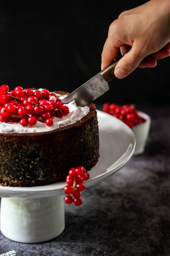 Mohntorte garniert mit Ribiseln steht auf Tortenständer