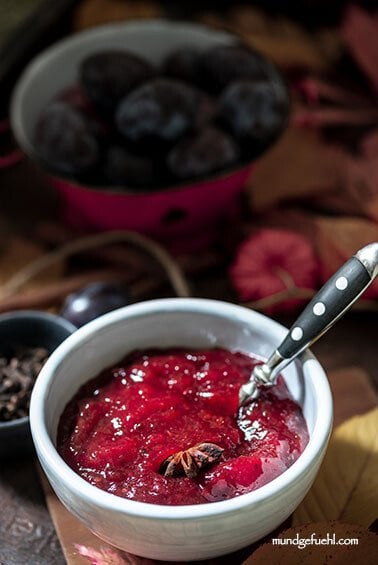 Eine Schale Pflaumenmarmelade steht neben einer Schale Pflaumen