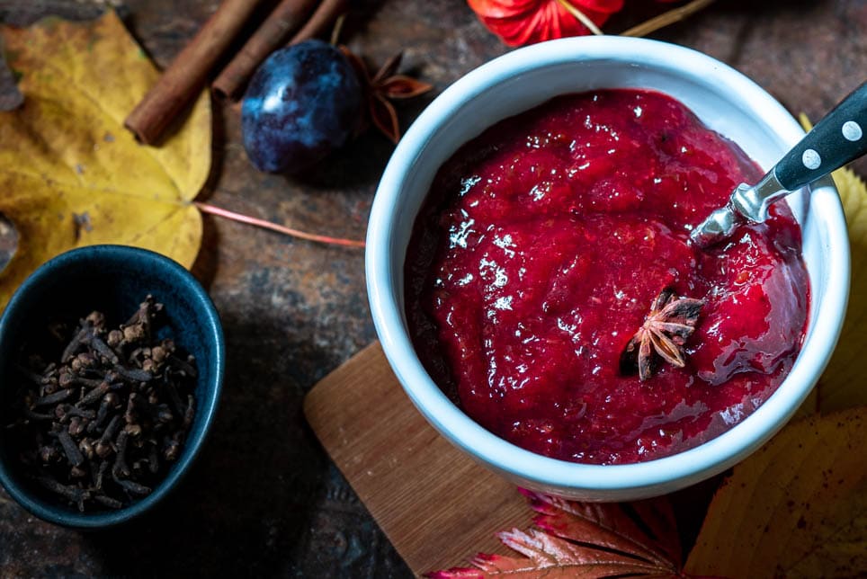 Eine Schale Pflaumenmarmelade steht neben einer Schale Pflaumen