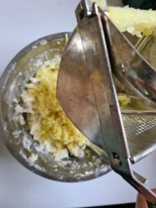 Kartoffeln in Kartoffelpresse für Topfenlaibchen