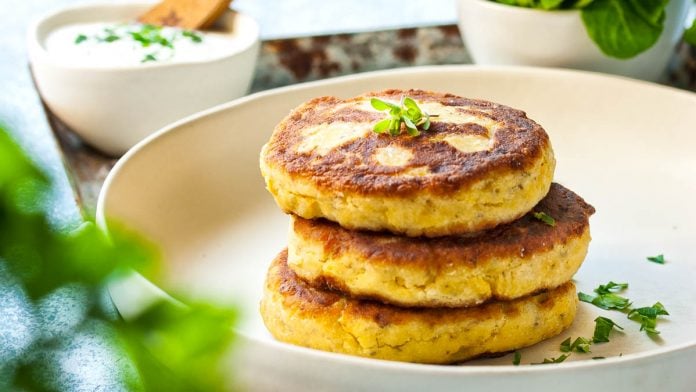 Topfenlaibchen auf einem Teller. Dahinter ein Dip und Salat