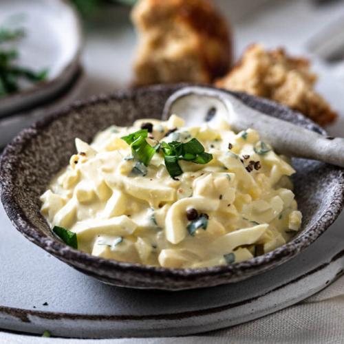 Ein Schälchen Eiersalat mit Bärlauch und Brötchen.