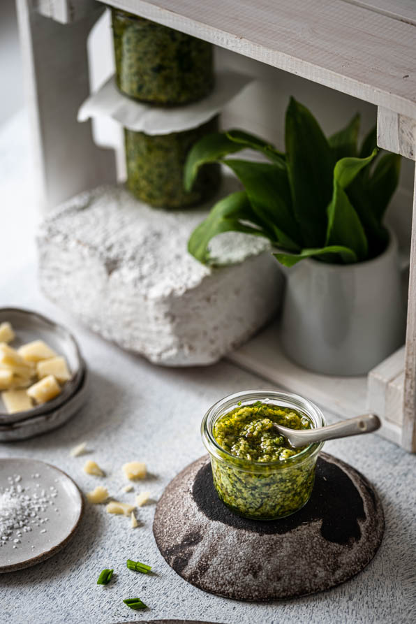 Bärlauch Pesto steht mit einzelnen Zutaten am Tisch