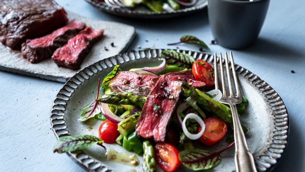 Spargelsalat mit aufgeschnittenem Rumpsteak auf einem Teller