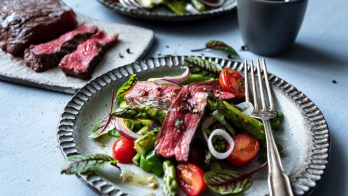 Spargelsalat mit aufgeschnittenem Rumpsteak auf einem Teller