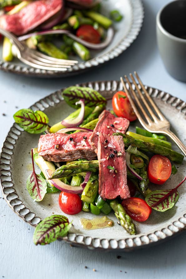Spargelsalat mit aufgeschnittenem Rumpsteak auf einem Teller