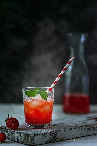 Ein Glas mit einem Erdbeer Shrub und einem Strohhalm