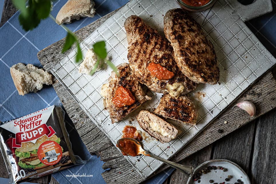 Pljeskavica liegt aufgeschnitten auf Brett