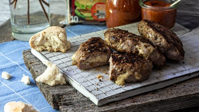 Pljeskavica liegt aufgeschnitten auf Brett