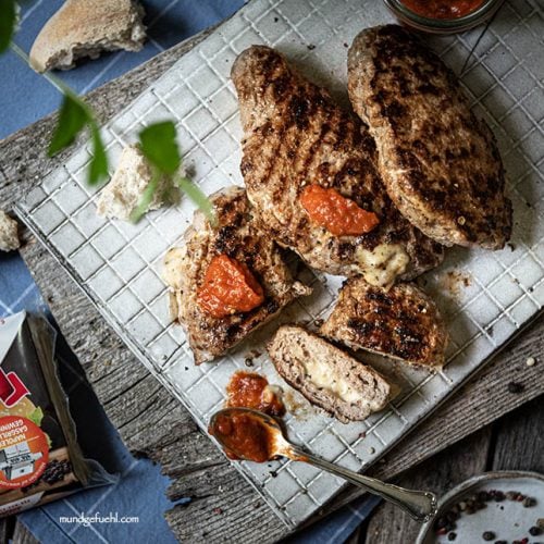 Pljeskavica liegt aufgeschnitten auf Brett