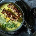 Maissuppe und zwei Putenspießen steht in Schüssel am Tisch