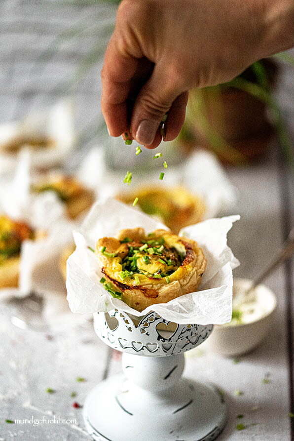 Jemand streut Schnittlauch auf Blätterteig Rose