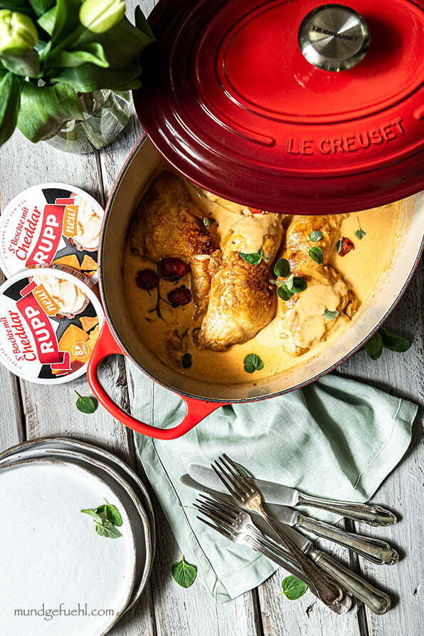 Huhn in einem Bräter mit Tomaten steht auf einem Tisch