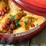 Huhn in einem Bräter mit Tomaten steht auf einem Tisch